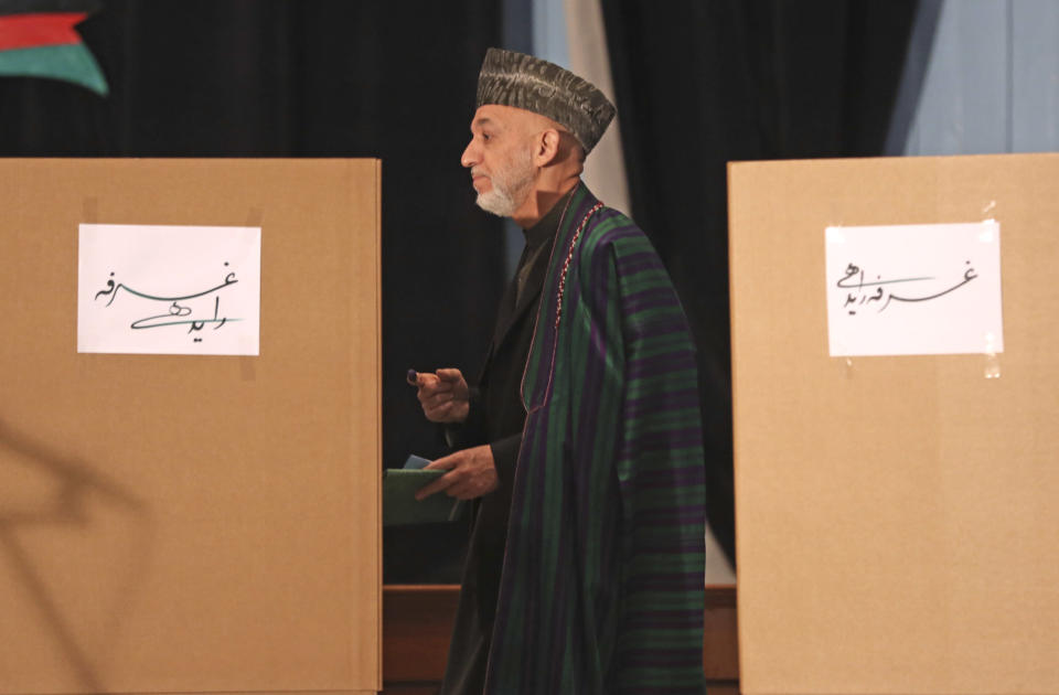 Afghan President Hamid Karzai, center, walks to the ballot boxes before he casts his vote at Amani high school, near the presidential palace in Kabul, Afghanistan, Saturday, April 5, 2014. (AP Photo/Massoud Hossaini)