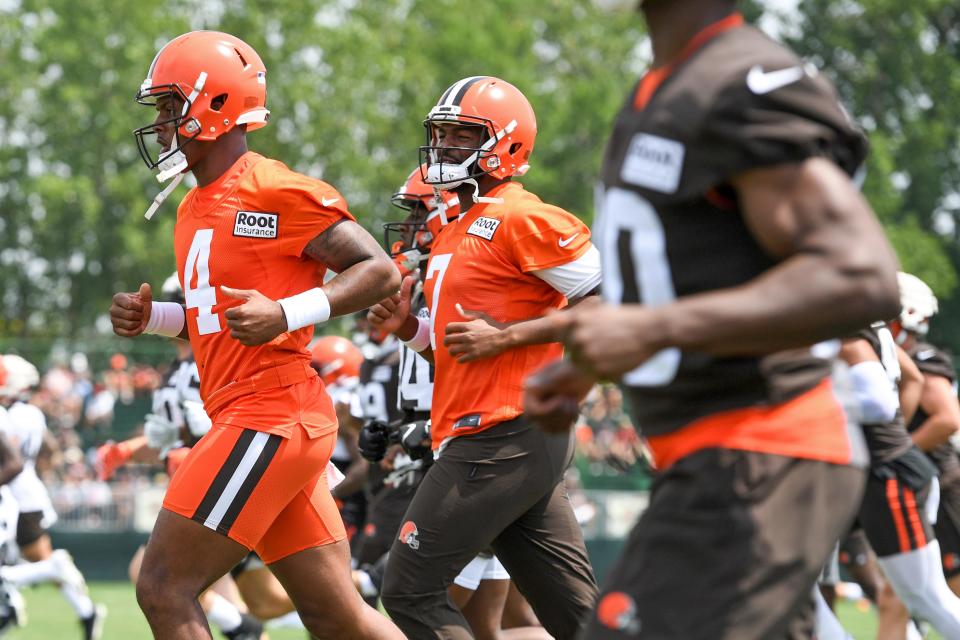 Cleveland Browns quarterbacks Deshaun Watson (4) and Jacoby Brissett (7) jog during the NFL football team's training camp, Monday, August 1, 2022, in Berea, Ohio. Watson was suspended for six games on Monday after being accused by two dozen women in Texas of sexual misconduct during massage treatments, in what a disciplinary officer said was behavior "more egregious than any before reviewed by the NFL."  (AP Photo/Nick Cammett)