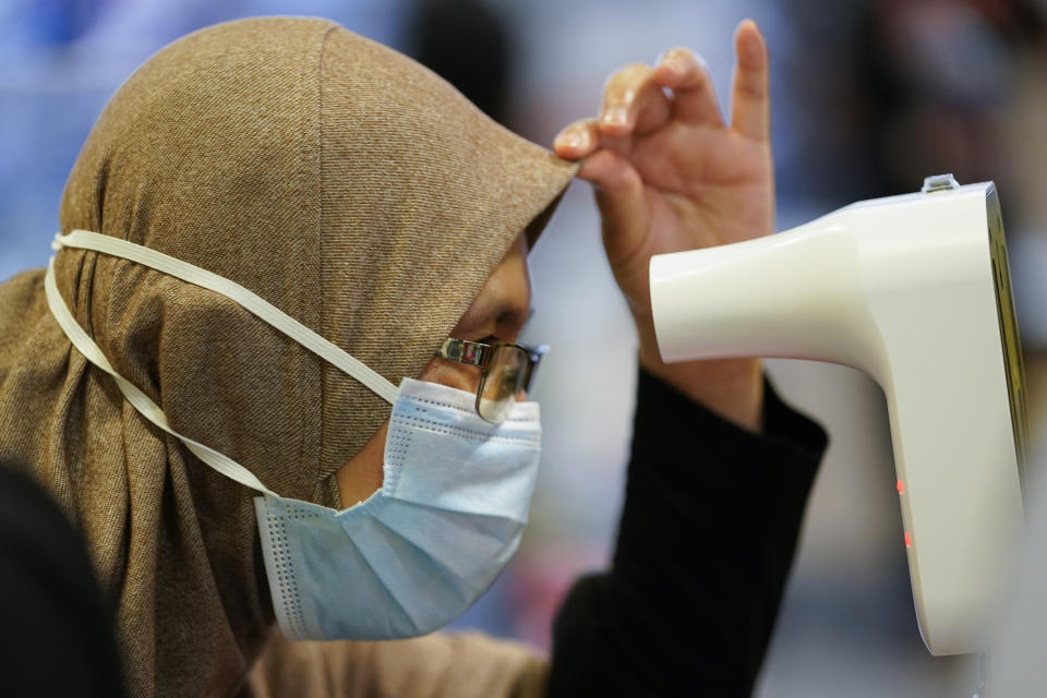 A Muslim women wearing a face mask to help curb the spread of the coronavirus measures her temperature at a shopping mall in Putrajaya, Malaysia, Thursday, Oct. 1, 2020. Thursday's new COVID-19 infections made it the second highest increase since the recovery movement control order (MCO) phase began on June 9. (AP Photo/Vincent Thian)