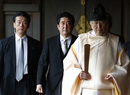 Japan's Prime Minister Shinzo Abe (C) is led by a Shinto priest as he visits Yasukuni shrine in Tokyo in this December 26, 2013 file photo. REUTERS/Toru Hanai