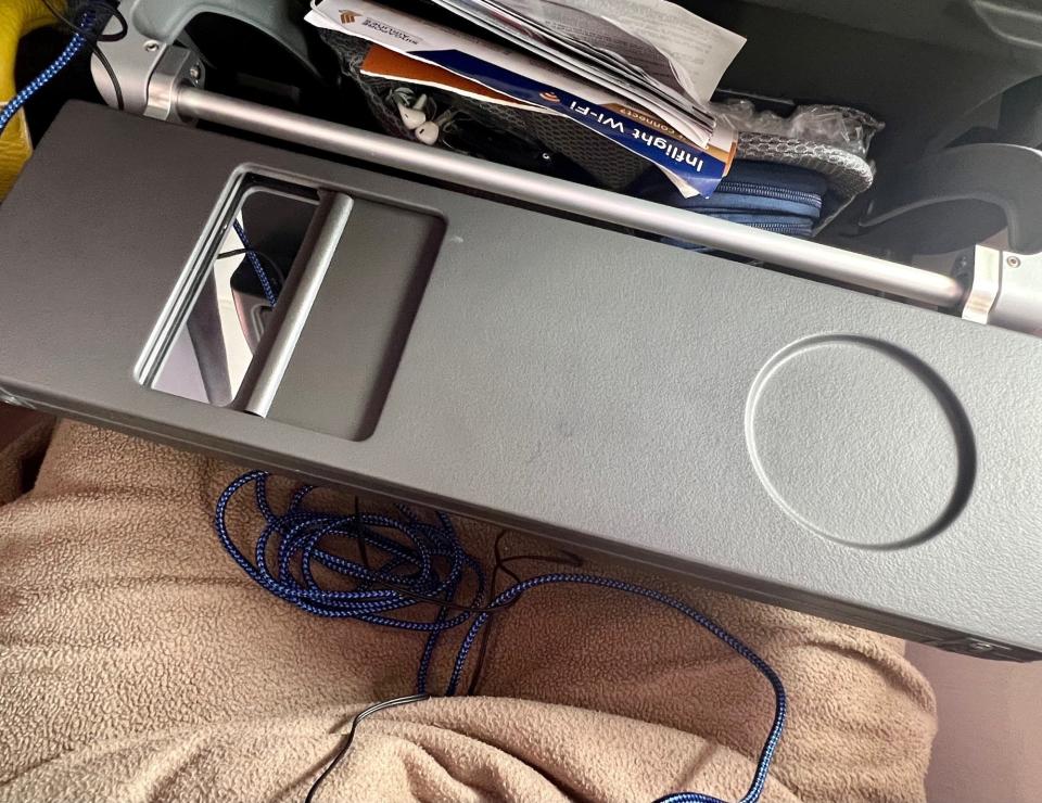 The tray table folded in half with a cupholder on the right and mirror on the left.