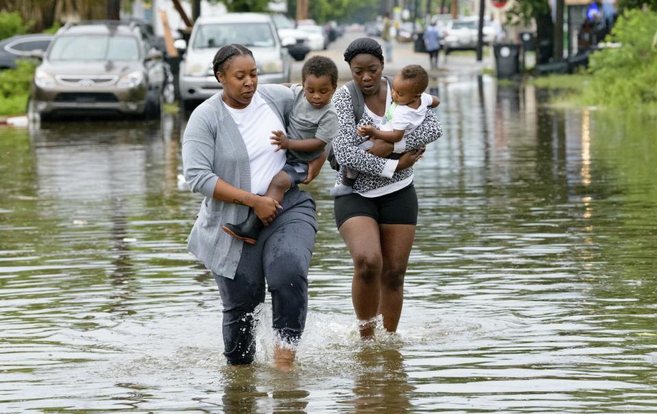 Jalana Furlough carries her son Drew Furlough as Terrian Jones carries Chance Furlough in New Orleans after flooding Wednesday, July 10, 2019. (AP Photo/Matthew Hinton)