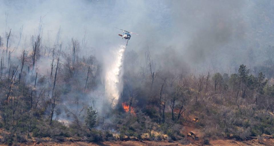 A helicopter drops water over the Thompson Fire near the Oroville Damn on Wednesday, July 3, 2024. Four firefighters and four structures have been lost in the fast moving wildfire that prompted evacuations for 13,000 residents.