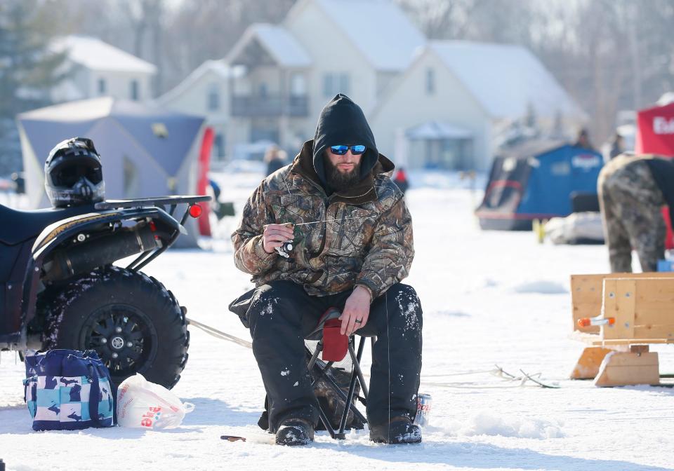 Joel Ihrig of Livonia drops a line into the water while ice fishing on Devils Lake Feb. 5, 2022, during the 70th annual Devils and Round Lake Men's Club Tip-Up Festival.