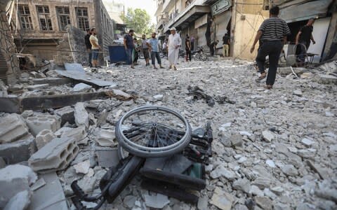 A wheelchair is seen amid the rubble of destroyed buildings following a reported regime air strike on the town of Ariha - Credit: OMAR HAJ KADOUR/AFP/Getty Images