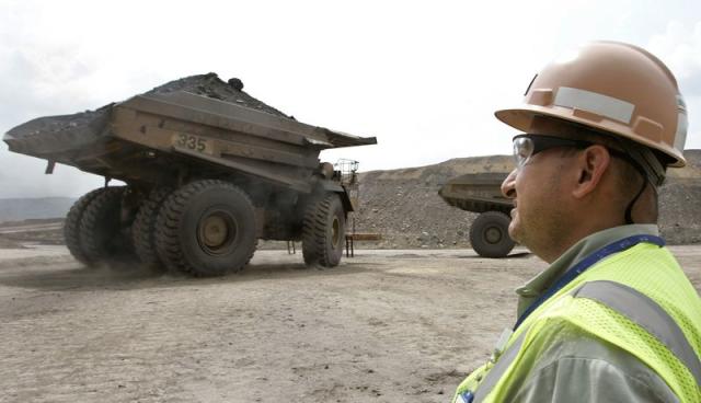 Foto de archivo. Un trabajador colombiano mira un camión minero que se aleja de la mina de carbón del Cerrejón, cerca del municipio de Barrancas, en el departamento de La Guajira