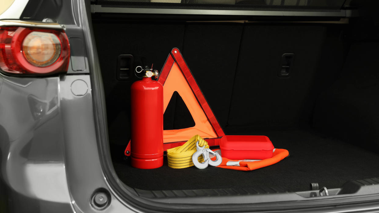  An open trunk of a car showing safety equipment including a warning triangle 