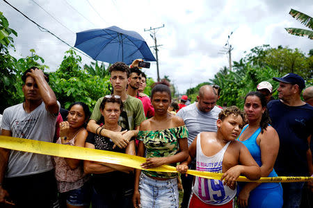 People look on near of the wreckage of a Boeing 737 plane that crashed in the agricultural area in Boyeros, around 20 km (12 miles) south of Havana, on Friday shortly after taking off from Havana's main airport in Cuba, May 18, 2018. REUTERS/Alexandre Meneghini