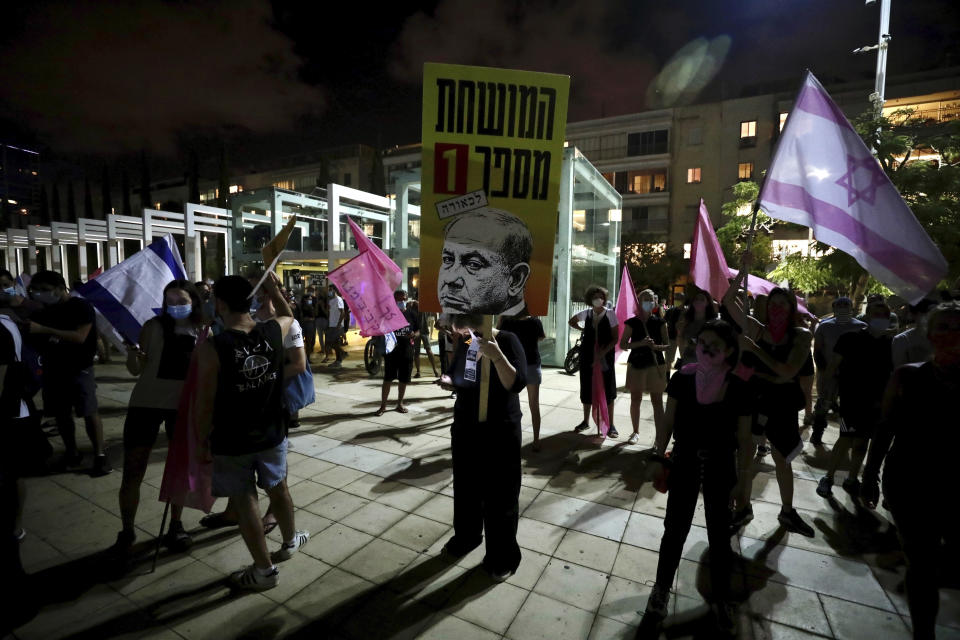 Israeli protesters wave flags and chant slogans during a demonstration against Israeli Prime Minister, Benjamin Netanyahu in Tel Aviv, Israel, Saturday, Oct. 10, 2020. (AP Photo/Sebastian Scheiner)