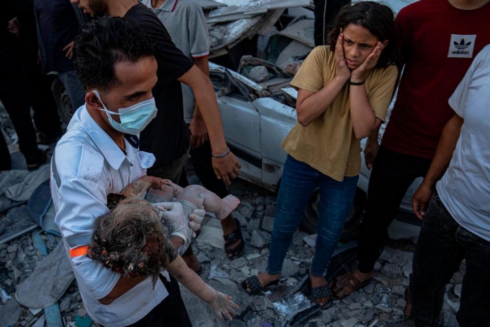 PHOTO: A Palestinian girl reacts as a child is carried from the rubble of a building after an airstrike in Khan Younis, Gaza Strip, Oct. 21, 2023.  (Fatima Shbair/AP)