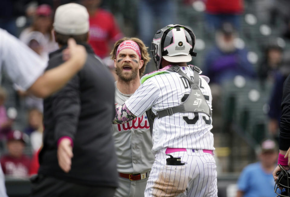 Philadelphia Phillies' Bryce Harper, center, is restrained by first base umpire Ben May, front left, and Colorado Rockies catcher Elias Diaz, right, as he reacts to a gesture from Rockies relief pitcher Jake Bird who retired the Phillies in the seventh inning of a baseball game Sunday, May 14, 2023, in Denver. (AP Photo/David Zalubowski)