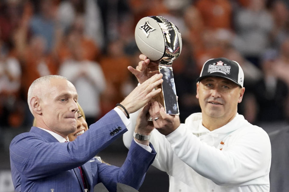 Big 12 Commissioner Brett Yormark, left, presents the trophy to Texas head coach Steve Sarkisian, right, after the Big 12 Conference championship NCAA college football game against Oklahoma State in Arlington, Texas, Saturday, Dec. 2, 2023. (AP Photo/Tony Gutierrez)