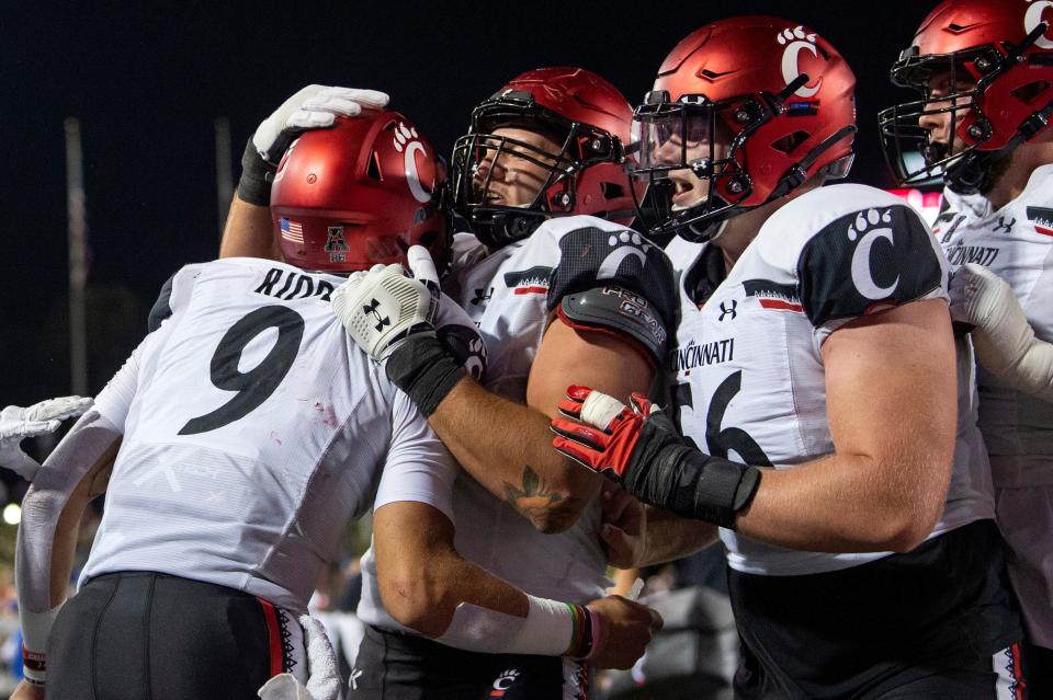 Cincinnati quarterback Desmond Ridder (9) is congratulated by offensive linemen Vincent McConnell, center, and Jake Renfro (56) after a touchdown run against SMU during the second half, Oct. 24, 2020, in Dallas. (AP Photo/Jeffrey McWhorter)