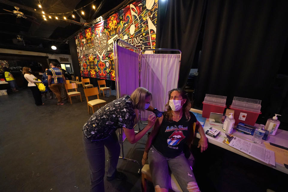 FILE - In this Tuesday, April 13, 2021 file photo, Allison Richter receives the Moderna COVID-19 vaccine from volunteer RN Maggie Baker, during a vaccine event hosted by Nola Ready, where people received a free drink at the bar if they received a COVID-19 vaccine, at The Howling Wolf, a music venue and bar, in New Orleans. (AP Photo/Gerald Herbert)