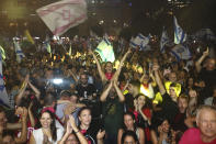 Israelis celebrate the swearing in of the new government in Tel Aviv, Israel, Sunday, June 13, 2021. Israel's parliament has voted in favor of a new coalition government, formally ending Prime Minister Benjamin Netanyahu's historic 12-year rule. Naftali Bennett, a former ally of Netanyahu became the new prime minister. (AP Photo/Oded Balilty)