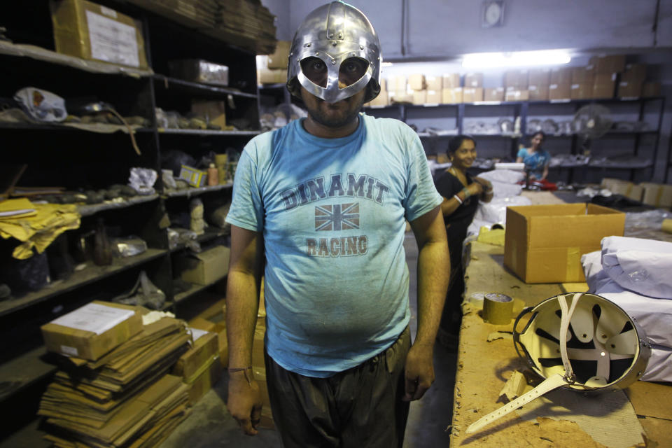 In this, June 2, 2012 photograph, a worker poses with a helmet being prepared for a Hollywood period movie at a workshop owned by Indian businessman Ashok Rai, unseen, in Sahibabad, India. From Hollywood war movies to Japanese Samurai films to battle re-enactments across Europe, Rai is one of the world's go-to men for historic weapons and battle attire.(AP Photo/Saurabh Das)