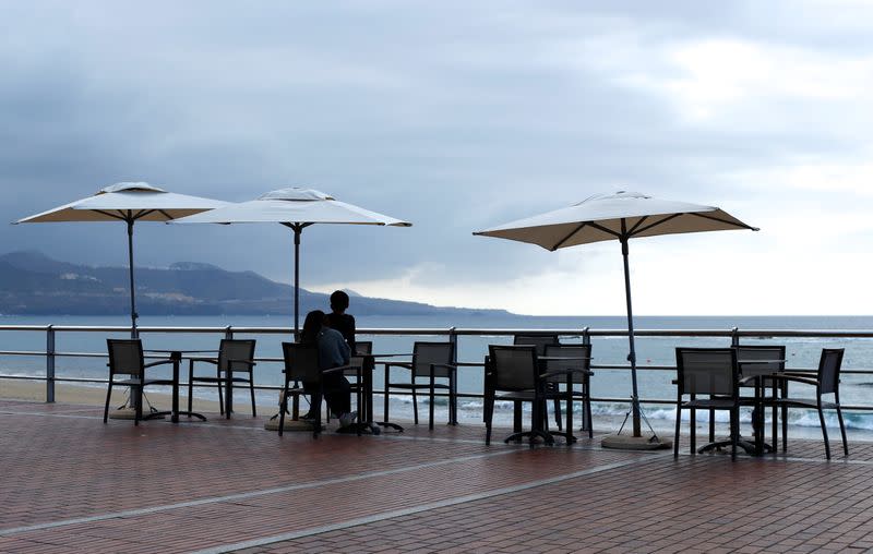 People sit on a terrace at Las Canteras beach, in Gran Canaria