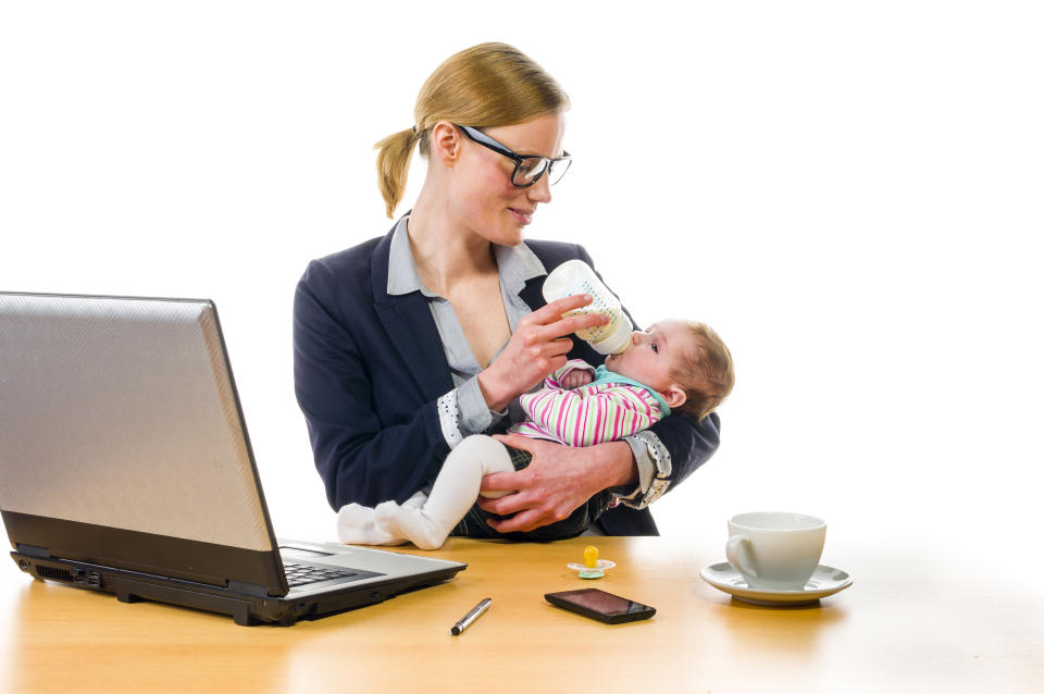 Adult business woman wearing a costume and supplied her newborn daughter in the office workplace, isolated against a white background.