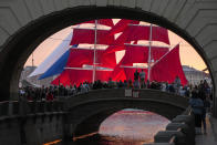 People watch a brig with scarlet sails sailing on the Neva River during a rehearsal for the Scarlet Sails festivities marking school graduation in St. Petersburg, Russia, late Thursday, June 23, 2022. The Scarlet Sails celebration is a rite of passage both figuratively and literally. Every year, tall ships with glowing red sails make their way down the Neva River in St. Petersburg to honor recent school graduates as they set out on the journey into adulthood. (AP Photo/Dmitri Lovetsky)