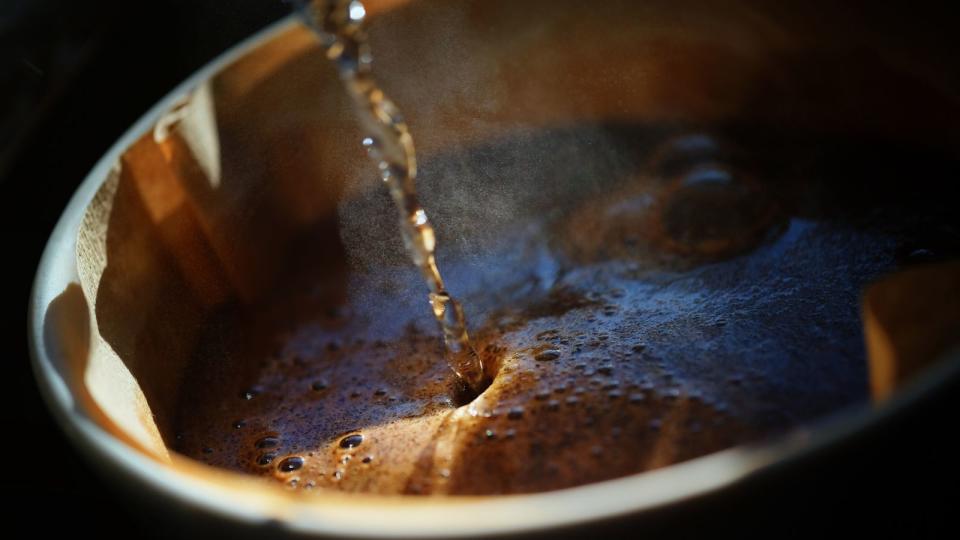 Hot water being poured into a cup of coffee with a thick crema