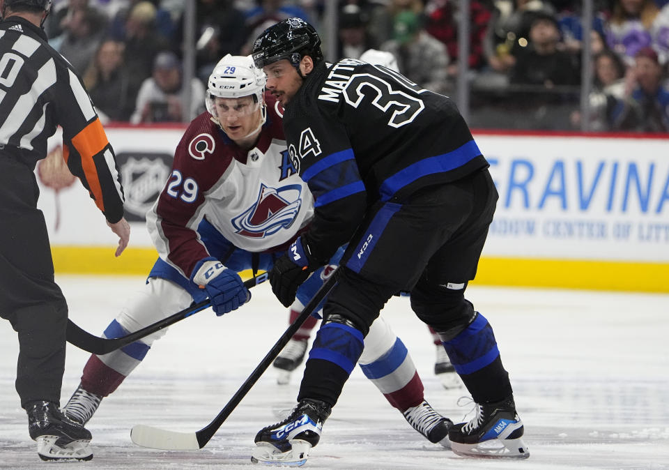 Toronto Maple Leafs center Auston Matthews, front right, and Colorado Avalanche center Nathan MacKinnon wait for the puck drop in the first period of an NHL hockey game Saturday, Feb. 24, 2024, in Denver. (AP Photo/David Zalubowski)