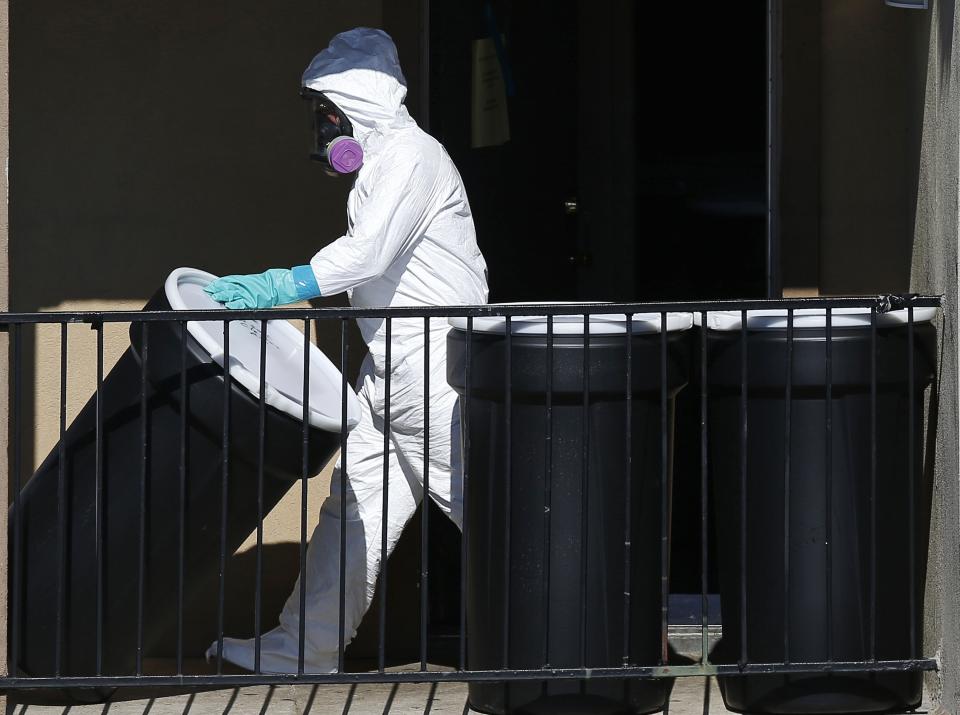 A worker in a hazardous material suit carries out a barrel of contents from the apartment unit where a man diagnosed with the Ebola virus was staying in Dallas, Texas, October 5, 2014. Thomas Eric Duncan, the first person diagnosed with Ebola in the United States, was fighting for his life at a Dallas hospital on Sunday and appeared not to be receiving any of the experimental medicines for the virus, a top U.S. medical official said. REUTERS/Jim Young (UNITED STATES - Tags: HEALTH)