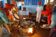 Members of a Hindu religious group Lal Mahendra Shiv Shakti Sewa Samiti prepare food to distribute to homeless people and stranded migrant workers during the lockdown due to the coronavirus pandemic in Prayagraj, India, Friday, April 17, 2020. The organization says they serve thousands of people daily at different regions in the city since the lockdown started in the country. (AP Photo/Rajesh Kumar Singh)