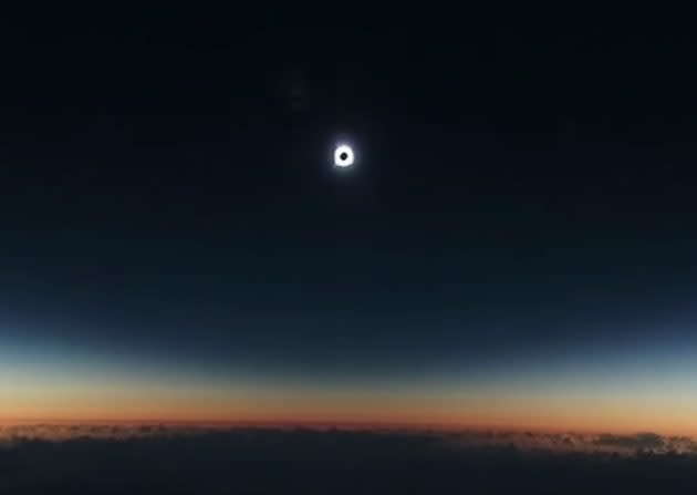 The black disk of a total solar eclipse hangs over the clouds during an Alaska Airlines flight in 2016. Passengers on an August flight should see a similar sight. (Robert Stephens via YouTube)