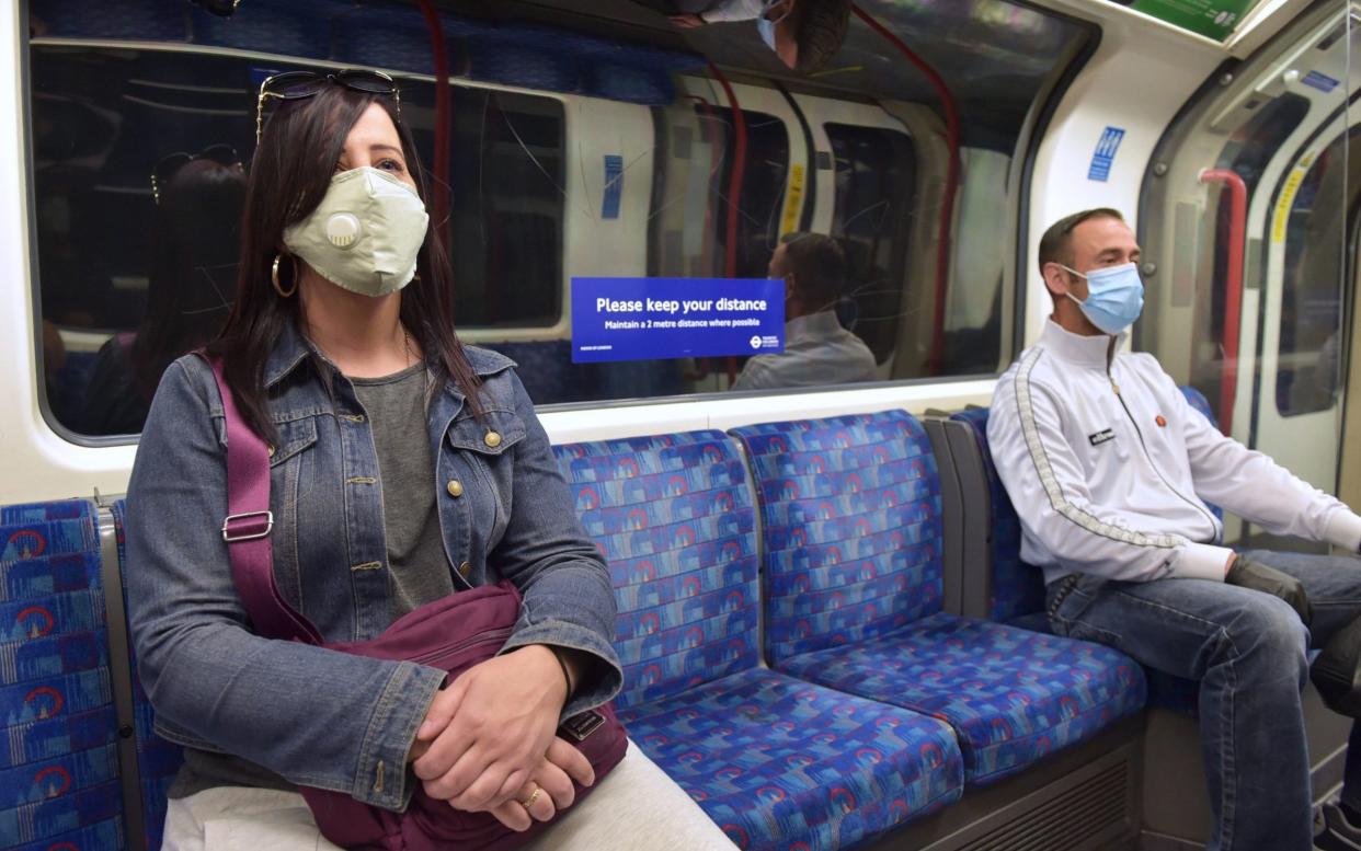 Passengers wear face masks on a Central Line underground train, following the announcement that wearing a face covering will be mandatory for passengers on public transport in England from June 15 - Two metre regulation could be relaxed if Britain gets accustomed to wearing face masks in public places - PA