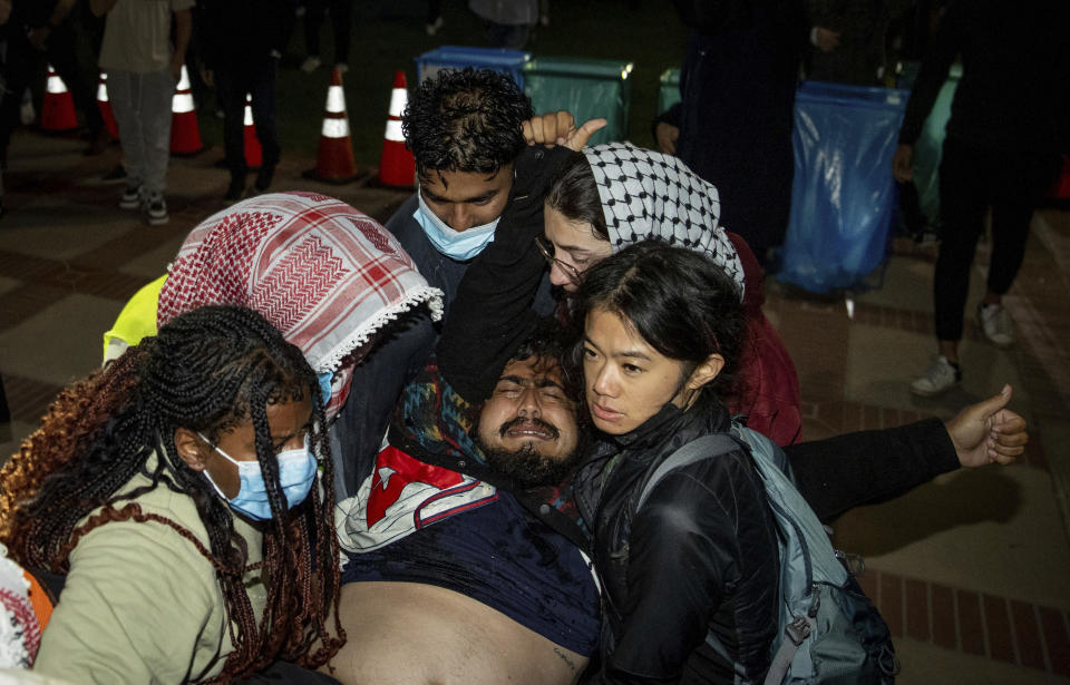 A person is carried away at a pro-Palestinian encampment at the University of California, Los Angeles late Tuesday, April 30, 2024, in Los Angeles. Dueling groups of protesters clashed at the school, grappling in fistfights and shoving, kicking and using sticks to beat one another. (AP Photo/Ethan Swope)