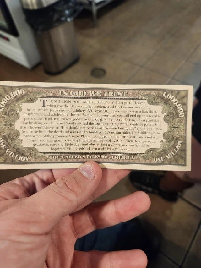 Hand holding a novelty 'million dollar' bill with Christian evangelism text