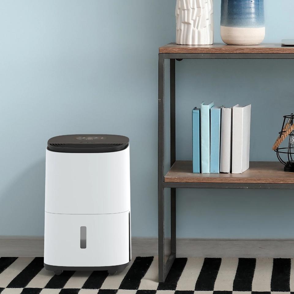 The MeacoDry Arete One dehumidifier next to shelves in a room with a blue wall