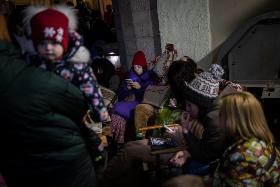 People sit in a basement, used as a bomb shelter, during an air raid in Lviv, Western Ukraine, Saturday, March 19, 2022.