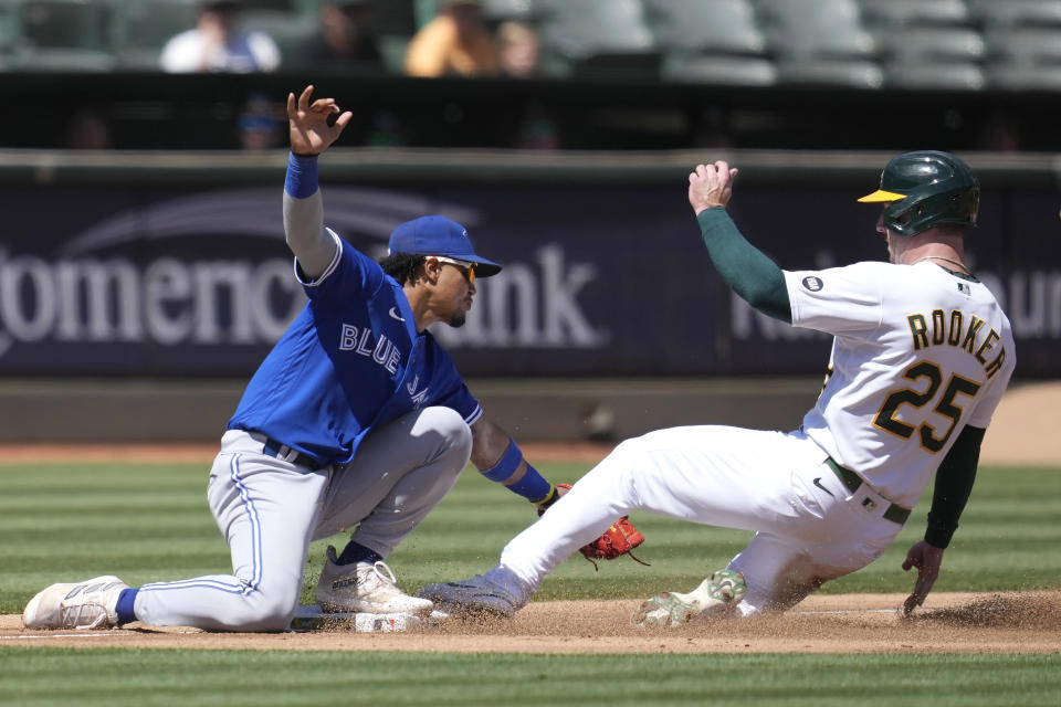 Toronto Blue Jays third baseman Santiago Espinal, left, tags out Oakland Athletics' Brent Rooker (25) during the fourth inning of a baseball game in Oakland, Calif., Wednesday, Sept. 6, 2023. (AP Photo/Jeff Chiu)