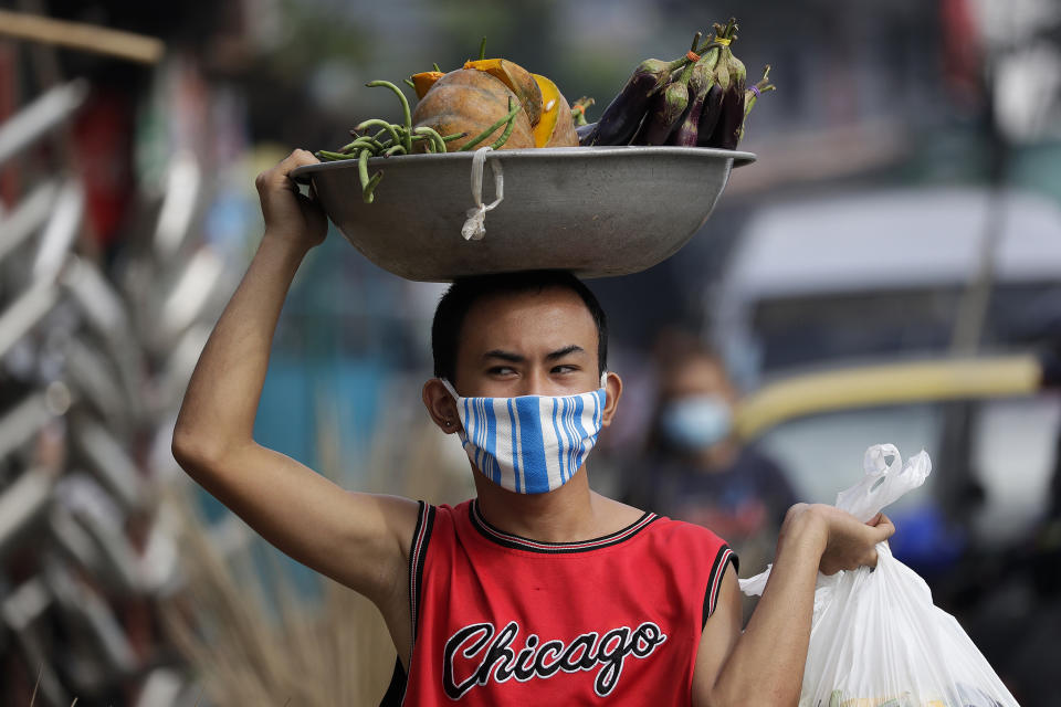 A man wears a mask to curb the spread of the coronavirus as he peddles vegetables at the outskirts of Manila, Philippines on Friday, Sept. 25, 2020. The brooms are sold from P30-P200 (about US 50 cents to US$4) each. (AP Photo/Aaron Favila)