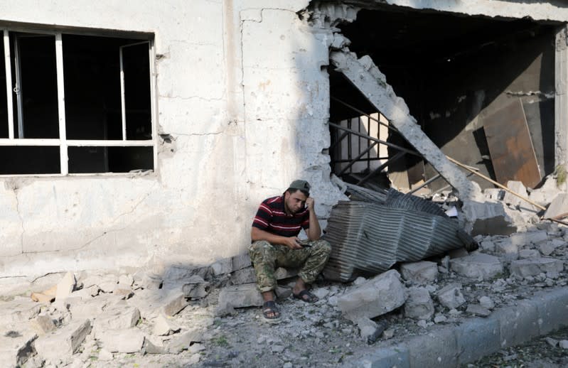 A Turkey-backed Syrian rebel fighter sits at the site of an explosion in the town of Tal Abyad