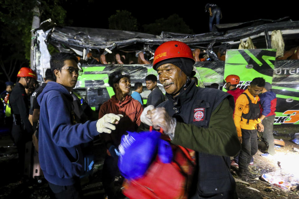Rescuers collect the belongings of victims from the wreckage of a bus after an accident in Subang, West Java, Indonesia, late Saturday, May 11, 2024. The bus carrying high school students and teachers returning from an outing smashed into cars and motorbikes in Indonesia's West Java province, killing a number of people on board. (AP Photo/Ryan Suherlan)