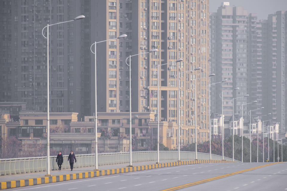 FILE - In this Tuesday, Jan. 28, 2020 file photo, people wearing face masks walk down a deserted street in Wuhan in central China's Hubei Province. Throughout January, the World Health Organization publicly praised China for what it called a speedy response to the new coronavirus. It repeatedly thanked the Chinese government for sharing the genetic map of the virus “immediately,” and said its work and its commitment to transparency were “very impressive, and beyond words.” But behind the scenes, it was a much different story, one of significant delays by China and considerable frustration among WHO officials over not getting the information they needed to fight the spread of the deadly virus, The Associated Press has found. (AP Photo/Arek Rataj)