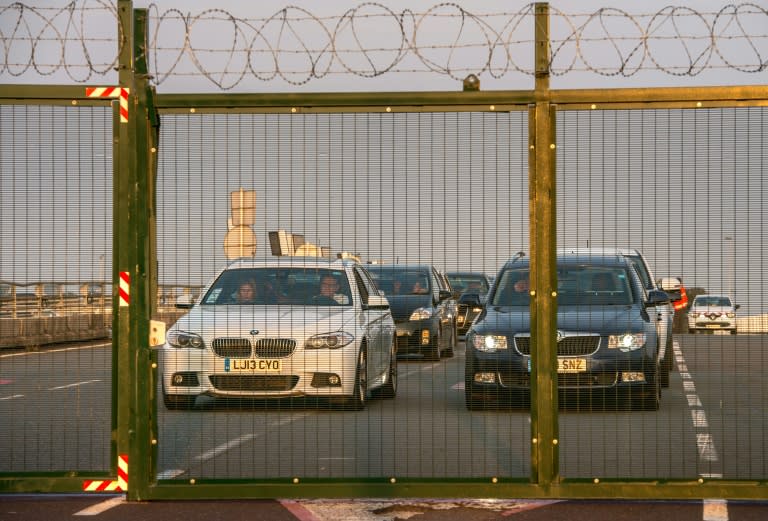 British vehicles wait behind fences topped with barbed wire which protect the boarding platform of the Eurotunnel site from the migrants who try to enter, in Coquelles near Calais, northern France, on July 31, 2015