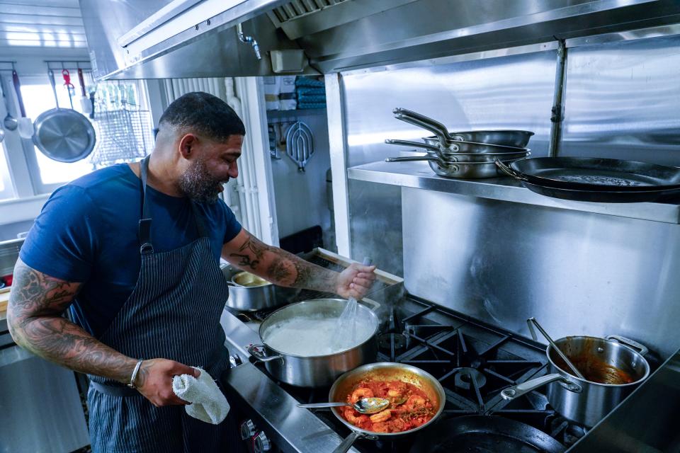 Digby Stridiron, chef and co-owner at Latha Restaurant & Bar, prepares shrimp moqueca, coconut rice grits and broccolini at the restaurant located within the Diaspora Collective in Phoenix on April 19, 2023.