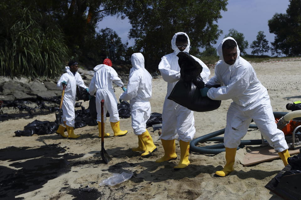 Workers clean oil spill along Sentosa's Tanjong Beach area in Singapore, Sunday, June 16, 2024. (AP Photo/Suhaimi Abdullah)