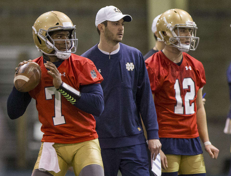 FILE - In this March 6, 2018, file photo, Notre Dame quarterback Brandon Wimbush (7) looks to throw the ball next to quarterbacks coach Tom Reese and teammate Ian Book (12) during NCAA college football practice in South Bend, Ind. Two people familiar with the decision say No. 3 Notre Dame will start Wimbush against Florida State on Saturday for Book, who is nursing an undisclosed injury. The people spoke Thursday, Nov. 8, 2018, to The Associated Press on condition of anonymity to because no official announcement was forthcoming. Notre Dame coach Brian Kelly had a scheduled news conference later Thursday. (Robert Franklin/South Bend Tribune via AP, File)