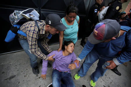 A Honduran migrant, part of a caravan trying to reach the U.S., is helped by others after arriving in Esquipulas city in Guatemala, October 15, 2018. REUTERS/Jorge Cabrera