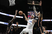 Los Angeles Clippers guard Terance Mann (14) passes the ball as he goes between Atlanta Hawks forwards Derrick Favors (15) and John Collins (20) during the first half of an NBA basketball game Saturday, Jan. 28, 2023, in Atlanta. (AP Photo/John Bazemore)