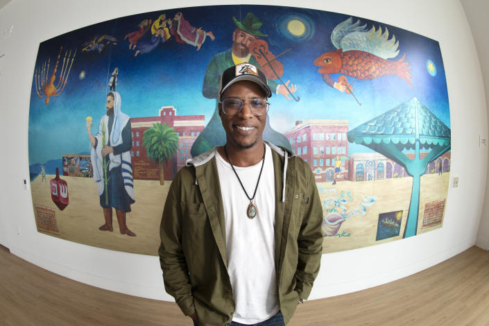 Nate Looney poses in front of a painting at the BAR Center at the Beach Thursday, June 16, 2022, in the Venice section of Los Angeles. Looney is a Black man who grew up in Los Angeles, a descendant of enslaved people from generations ago. He's also an observant, kippah-wearing Jew. (AP Photo/Mark J. Terrill)