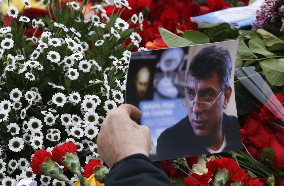 A visitor holds a photo at the site where Boris Nemtsov was recently murdered, in central Moscow, February 28, 2015. Russia's Investigative Committee is pursuing several lines on inquiry following the murder of opposition politician Boris Nemtsov, including the possibility it was an attempt to destabilise the political situation, Interfax news agency said. REUTERS/Sergei Karpukhin (RUSSIA - Tags: POLITICS CRIME LAW)