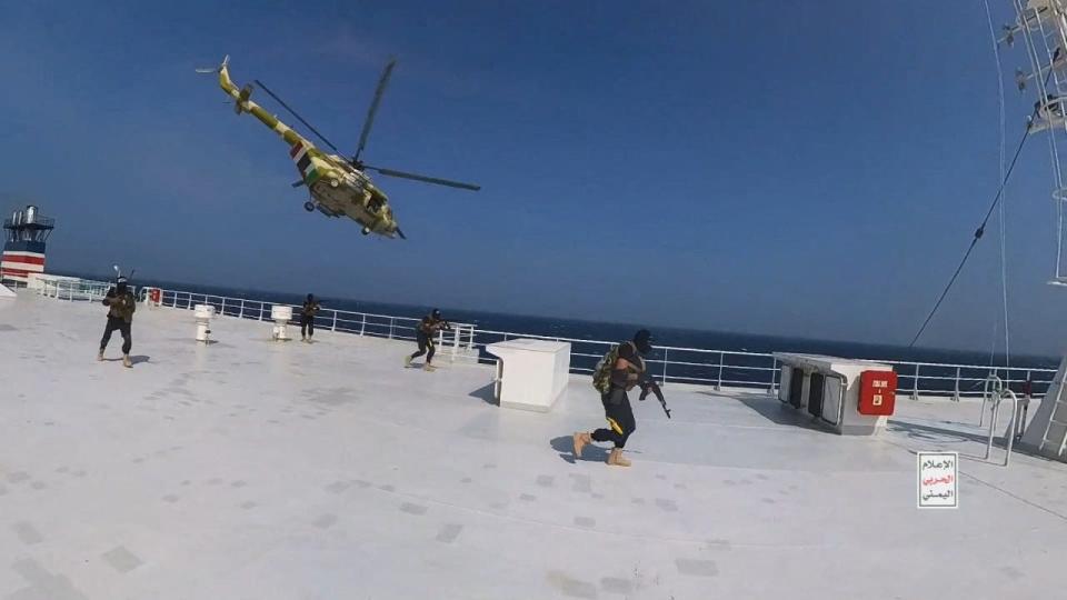 Houthi military helicopter hovers over the Galaxy Leader cargo ship as Houthi fighters walk on the ship's deck in the Red Sea in this photo released November 20, 2023.