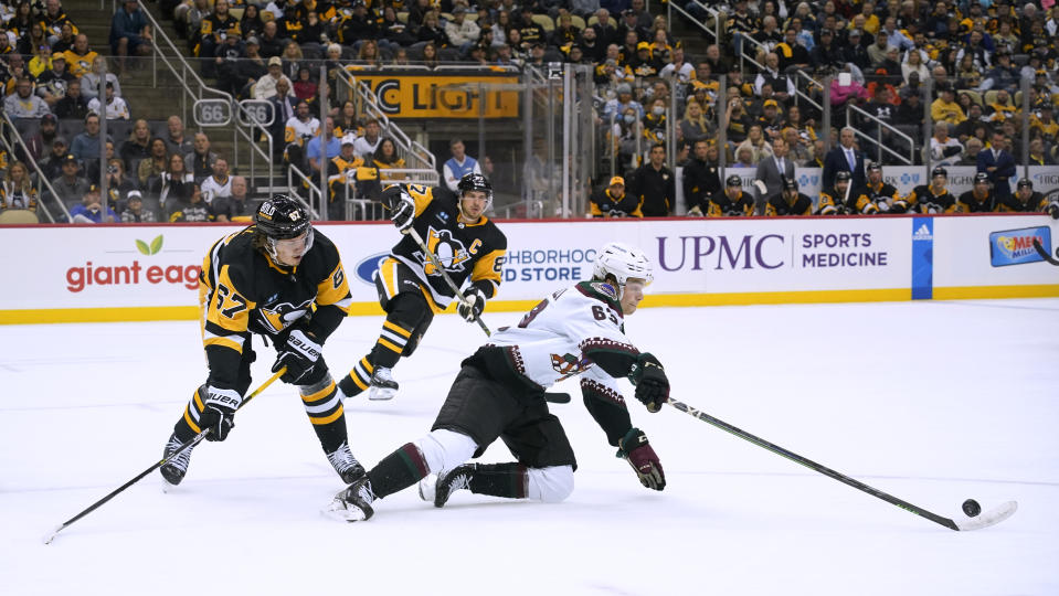 Arizona Coyotes' Matias Maccelli, right, controls the puck from his knees, next to Pittsburgh Penguins' Rickard Rakell (67) during the second period of an NHL hockey game Thursday, Oct. 13, 2022, in Pittsburgh. (AP Photo/Keith Srakocic)