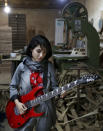 In this July 20, 2018 photo, Afghan musician Soraya Hosseini, a member of the Arikayn rock band, plays guitar at a furniture workshop in Eslamshahr, outside Tehran, Iran. Like others in Iran's vibrant arts scene, Afghan musicians must contend with hard-liners who view Western culture as corrupt and object to women performing in public. (AP Photo/Ebrahim Noroozi)