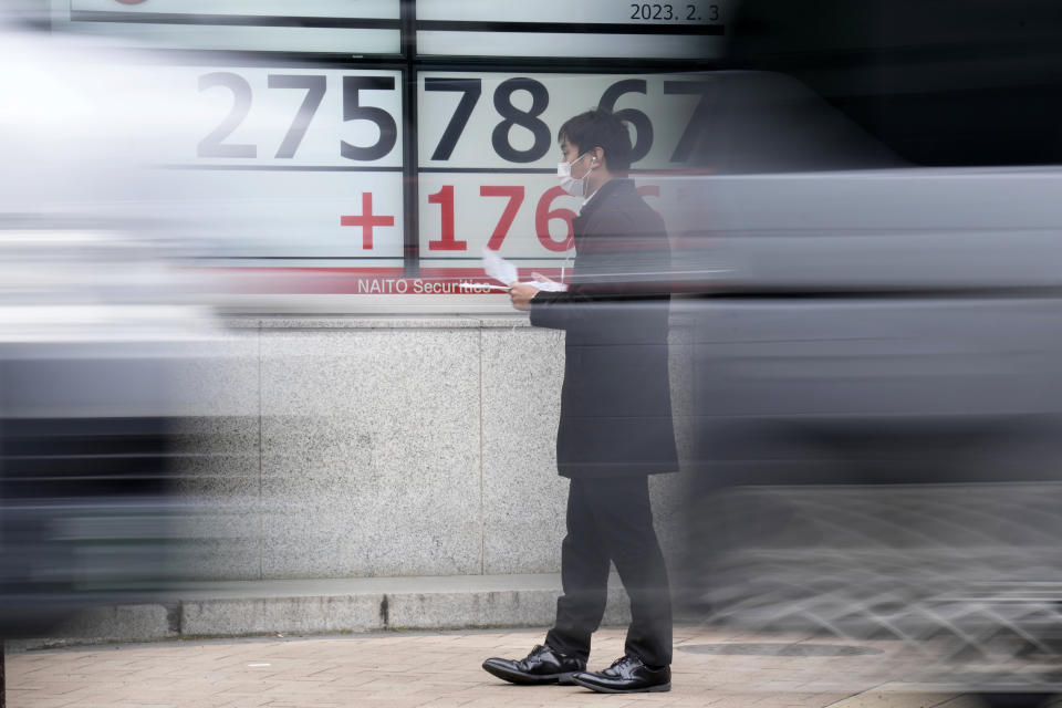 A person wearing a protective mask walks in front of an electronic stock board showing Japan's Nikkei 225 index at a securities firm Friday, Feb. 3, 2023, in Tokyo. Asian shares were trading mixed Friday ahead of a closely watched U.S. jobs report that may affect global interest rates. (AP Photo/Eugene Hoshiko)